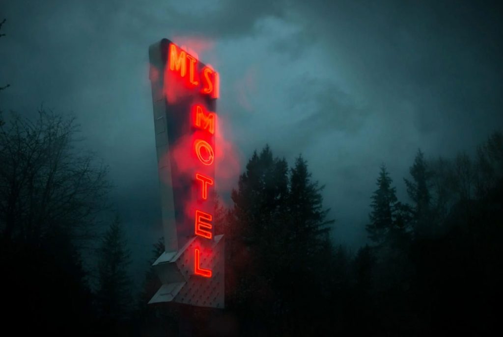 Photo de l'enseigne d'un motel à travers une vitre de voiture avec de la pluie sur la vitre